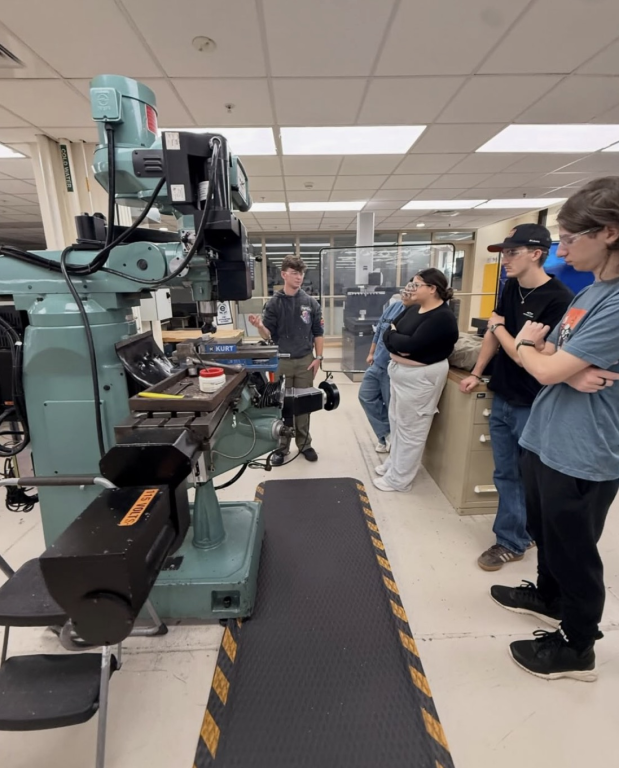 Students gathered around a milling machine in a Wentworth machine shop.
